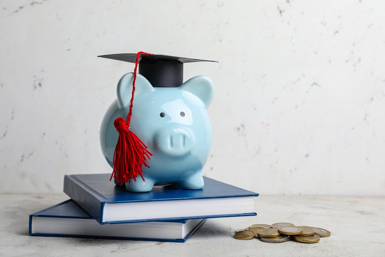 Piggy Bank with Graduation Hat and Books on Table. Tuition Fees Concept